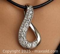 Silver pendant shown from front side, highlighting its polished silver finish and clear stones embedded on one side of the loop design.