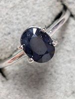Close-up of the blue sapphire gemstone set in sterling silver ring, showing the deep blue color and faceted oval shape.
