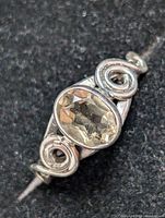 Close-up photo of silver ring showing oval faceted smokey quartz stone set in the center with decorative silver swirls on sides