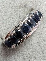 Close-up image of silver ring showing black faceted stones on the band from a slight angled top view.