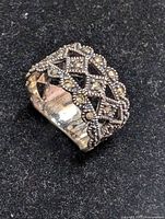 Close-up of the front and side of the silver ring showing marcasite stone pattern on black background.