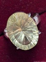 Close-up image of oval lemon quartz silver ring from a top angle showing gem facets and prong setting.