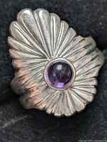 Front angled view of sterling silver ring showing sunburst design and round bezel amethyst stone.