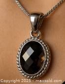 Front view of smokey quartz pendant on chain, showing faceted oval stone and silver rope border.