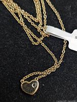 Sterling silver necklace chain visible on dark background with heart pendant attached including a small round sapphire stone.