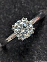 Close-up front view of sterling silver ring with round-cut moissanite stone in six prong setting on smooth band.