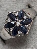 Close-up front view of sterling silver ring with blue sapphires and diamond accents in hexagonal cluster.