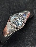 Close-up of the oval aquamarine set in the sterling silver ring showing the stone's faceting and color with milgrain bezel setting.