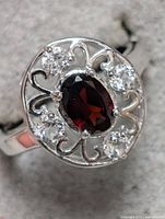 Close-up image of sterling silver ring with garnet center and clear stones