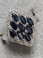Close-up photo of the sterling silver ring with blue sapphire stones arranged in marquise cuts in a diamond-shaped cluster accented with small silver beads.