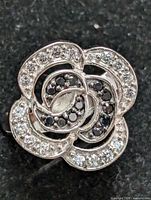 Close-up image of the front floral design of the sterling silver ring highlighting clear and black stones.