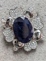 Close-up photo of the sterling silver ring with blue sapphire oval stone and surrounding heart-shaped clusters of cubic zirconia stones.