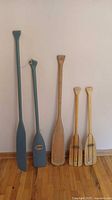 Five oars leaning against wall showing relative sizes and finishes