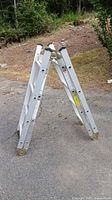 Full view of folded aluminum A-frame ladder on pavement