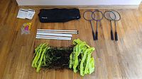 Full kit laid out: carry bag, instruction booklet, six poles, net, rackets, accessory bag