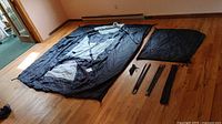 Tent body, rainfly, bag, poles and stakes laid out on floor