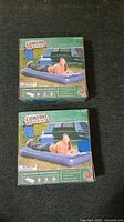 Two boxed Comfort Quest inflatable beds on dark carpet
