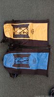 Front view of both dry bag backpacks showing yellow and blue panels with bungee cords