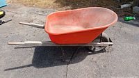 Side view showing red plastic tub, wooden handles, metal frame, tire