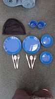Full set layout: plates, bowls, cups, utensils, pouch visible