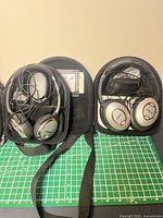 Two Bose headphones inside open zip cases with cables