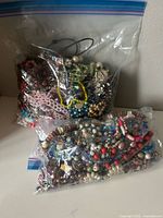 Two resealable bags filled with assorted beaded costume jewelry on table