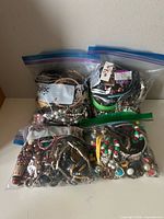 Four clear Ziploc bags filled with assorted costume jewelry pieces