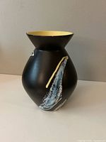 Full view of vase front showing matte black body and abstract streak