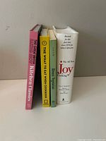 Four cookbooks standing upright showing spines: Kitchen Classics, The What to Eat When Cookbook, Almost Vegetarian, Joy of Cooking