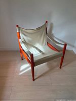Front angled view of orange beech frame safari chair with beige canvas sling