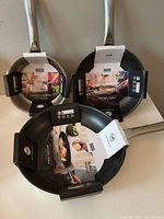 Three pans with packaging visible, showing diameters and non-stick interior