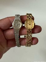 Silver-tone and gold-tone Seiko watches side by side in hand for scale
