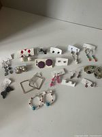 All 17 pairs of assorted earrings laid out on surface