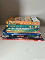 Stacked view of nine Pokémon books showing spines for reference and count