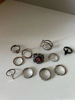 All 11 rings laid out on surface showing variety of designs and finishes