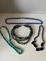 All four beaded necklaces laid out on white surface