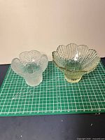 Both clear pressed glass flower-shaped bowls side by side
