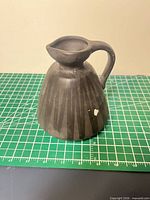 Front view of matte black ceramic pitcher on cutting mat