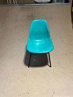 Front view of teal fiberglass chair on black metal legs