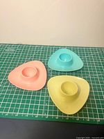 Three pastel plastic egg cups on cutting mat