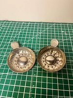 Top view of both silver-plated tastevins showing interior details and thumbpieces