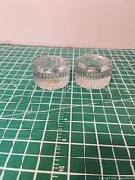 Two clear glass tealight holders, side view showing ribbed exterior and overall size reference