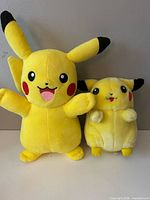 Front view of both Pikachu plush toys