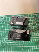Front view of both Ricoh cameras with lens covers closed and wrist straps visible