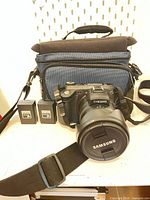 Front view of Samsung Pro815 camera with strap, lens cap, two batteries and camera bag