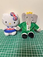 Front view of Hello Kitty and Babar plush on cutting mat for scale reference
