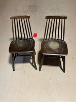 Front view of two spindle-back chairs showing wear on seats