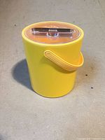 Full view of yellow vinyl ice bucket with handle and clear lid