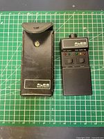 Breathalyzer and carrying pouch side by side on grid mat