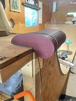 Side view of burgundy felt-covered lamp clamped to edge, cord visible